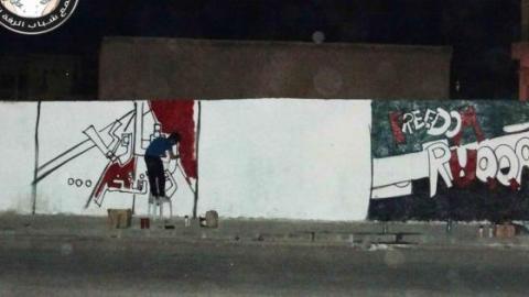صورة رسام غرافيتي اثناء قيامه برسم جدارية في مدينة الرقة .... المصدر صفحة شباب الرقع الحرَ على الفيس بوك