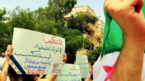 لافتة مرفوعة في أحد تظاهرات التجمع في مدينة حمص. المصدر: الصفحة الرسمية للتجمع