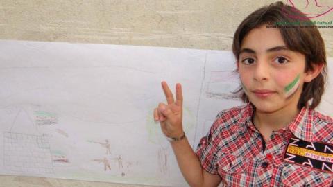 أحد الأطفال المشاركين في دورة التفريغ النفسي في المليحة وعلى وجهه علم الاستقلال(الثورة). المصدر: المنظمة السورية للمرأة والطفل