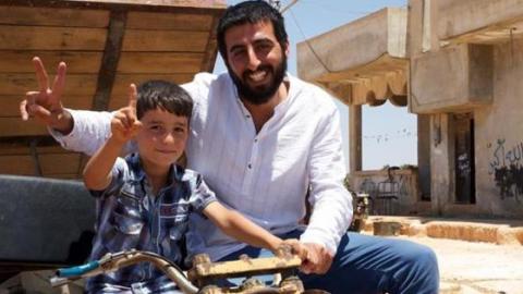 Syrian journalist Amer Matar with a child in the city of Banash, Idlib. Source: Amer Matar´s facebook page.