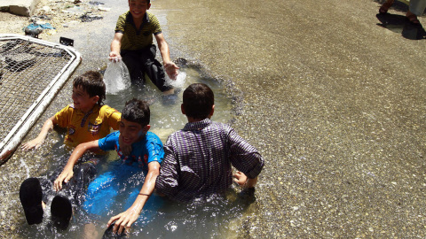 صورة لأطفال من تصوير حميد الخديب يلعبون في بالماء في حفرة ناتجة من صاروخ في حلب في حي الشعار،المصدر رويترز