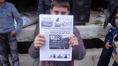 A child holding the newspaper. Source: Enab Baladi's Facebook page.