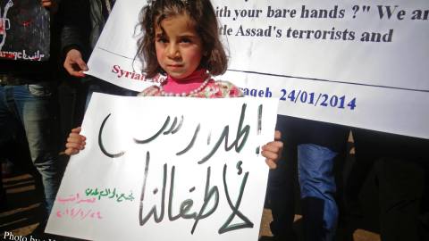 صورة لطفلة نازحة تحمل لافتة تطالب بفتح المدارس، المصدر الموقع الرسمي للحملة عالفيسبوك.