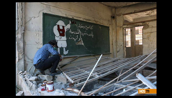 Abu Malik with one of his graffiti. Source: Humans of Syria.