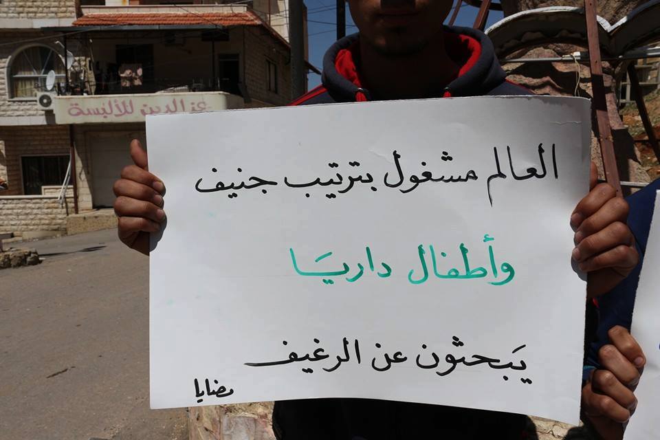 [“As the world is busy planning the Geneva talks, children are looking for a loaf of bread,” reads a sign held by a Madaya resident in solidarity with Darayya./Source: The Local Council of Darayya, Facebook - Madaya - 19-4-2016].