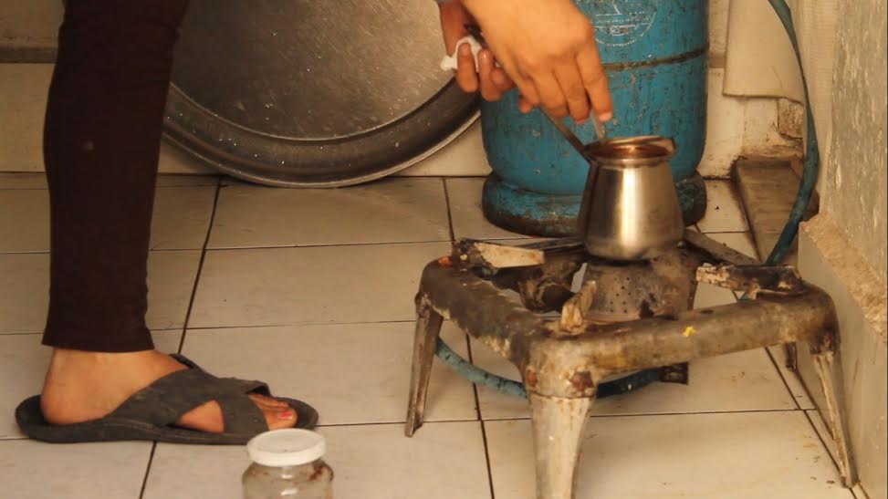 [Photo: Huda, who lost her leg, while she prepares coffee at her home - March 2016. (Source: Syria Untold)].