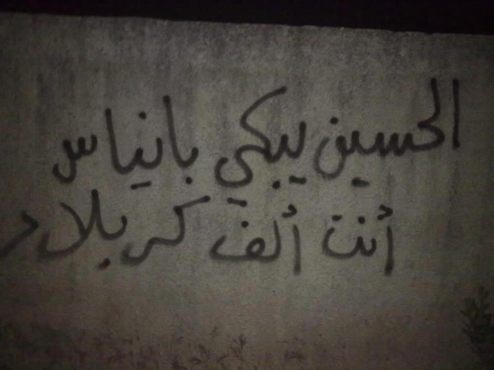 [Photo: A slogan written by Ayman in rural Jablah. It reads “Husayn weeps Banyas, you are a thousand Karbala'” (SyriaUntold)].