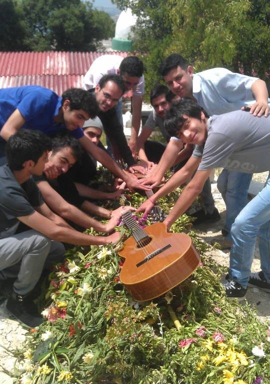 [Photo: Suleiman’s friends around his tomb on the one year anniversary of his death (SyriaUntold)].